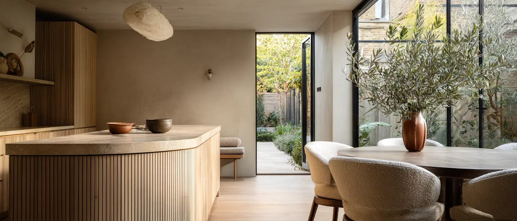 A limed oak kitchen with a curved fluted island opening onto a London garden