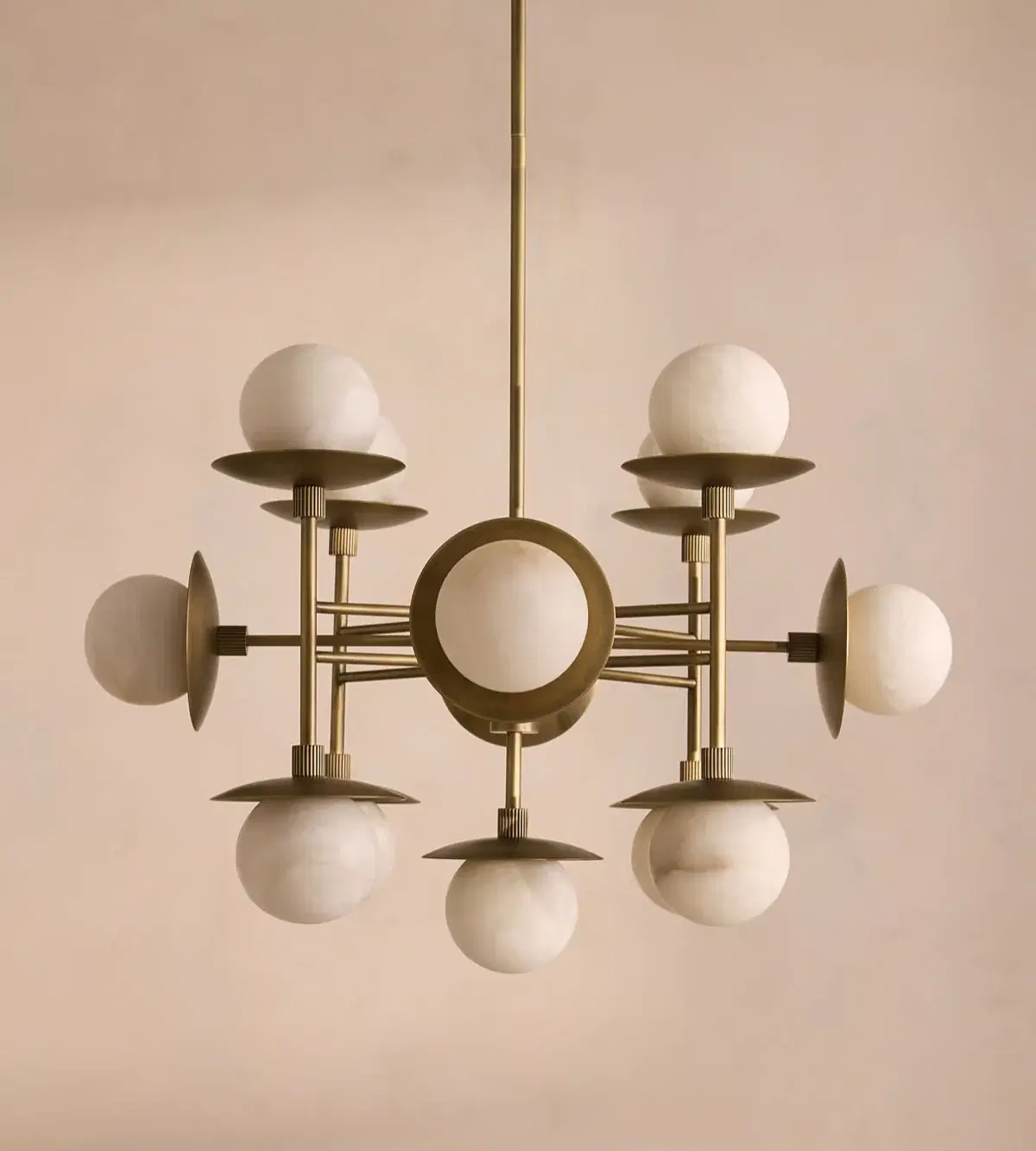 An aged brass chandelier with alabaster globes against a warm plaster wall